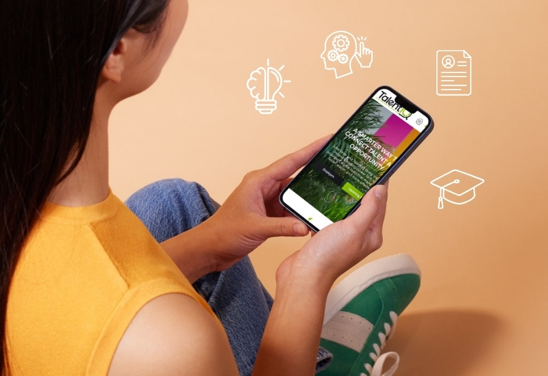 A person holding a smartphone displaying an educational app, sitting against a peach-colored background. Icons representing ideas, a document, and graduation are illustrated around the phone.