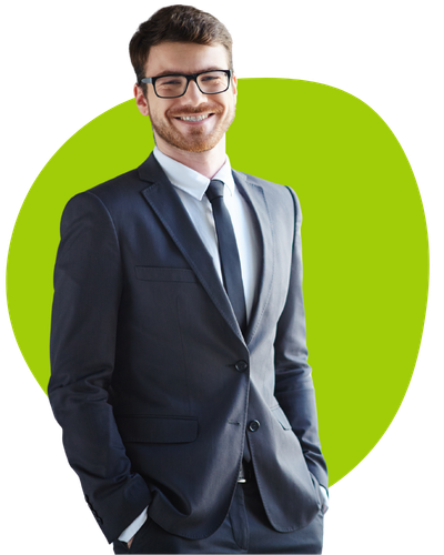 A confident man in a dark suit and tie, wearing glasses, stands with his hands in his pockets and smiles. Behind him is a vibrant green background that adds contrast to his formal attire.