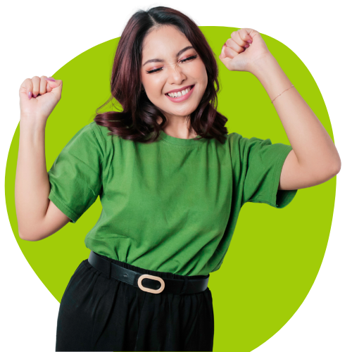 A smiling woman wearing a green t-shirt and black pants raises her hands in celebration against a bright green background.